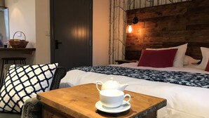 A neatly arranged hotel room with a bed, a wooden nightstand with a teapot, a chair, and a wall with a tree mural. - The Crown - Hutton le Hole (York)