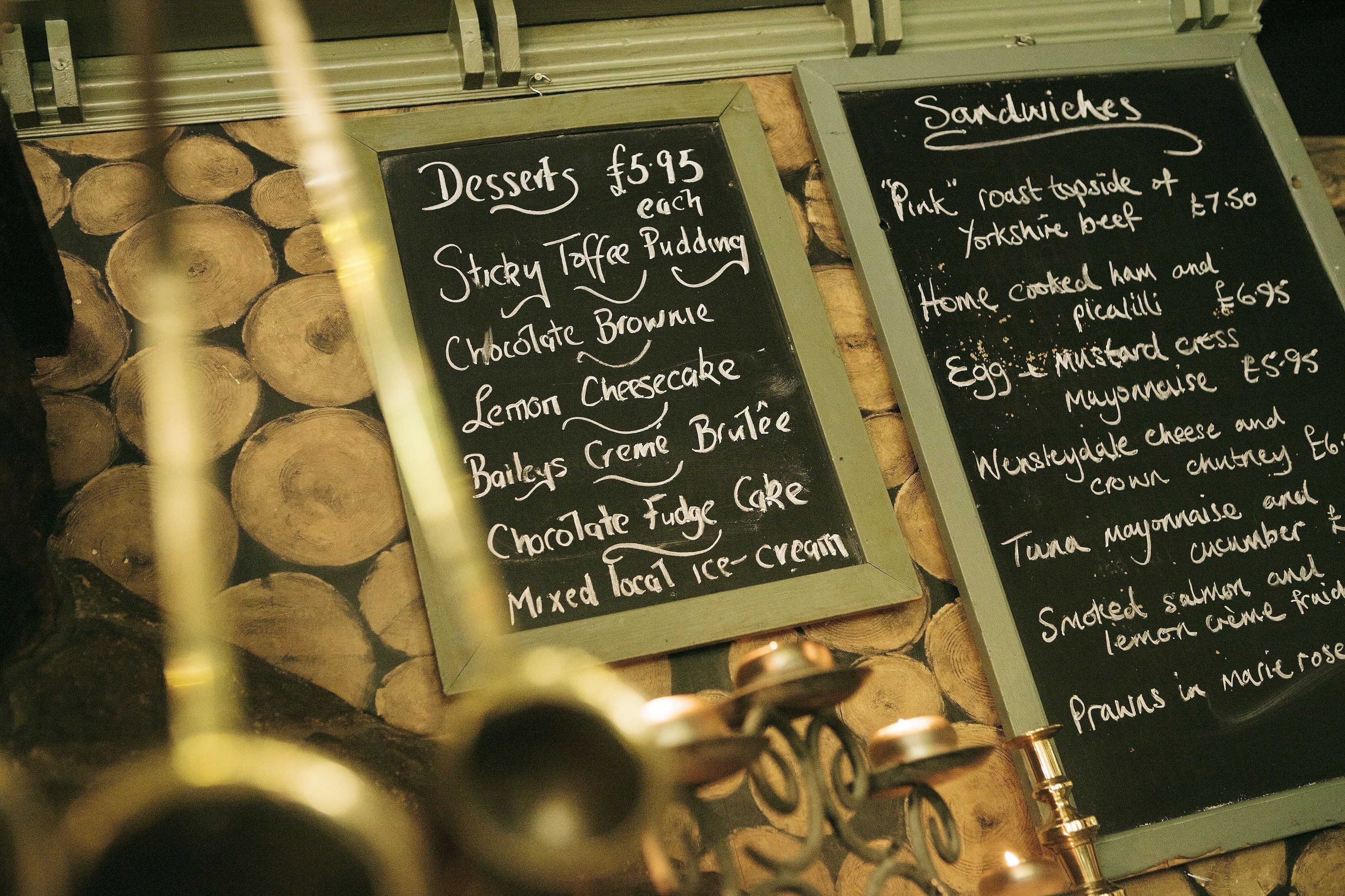 Two blackboards with food items and prices listed.