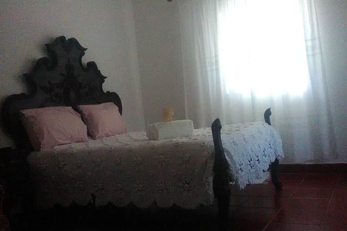 A bedroom with a bed, a nightstand, and a window with curtains.