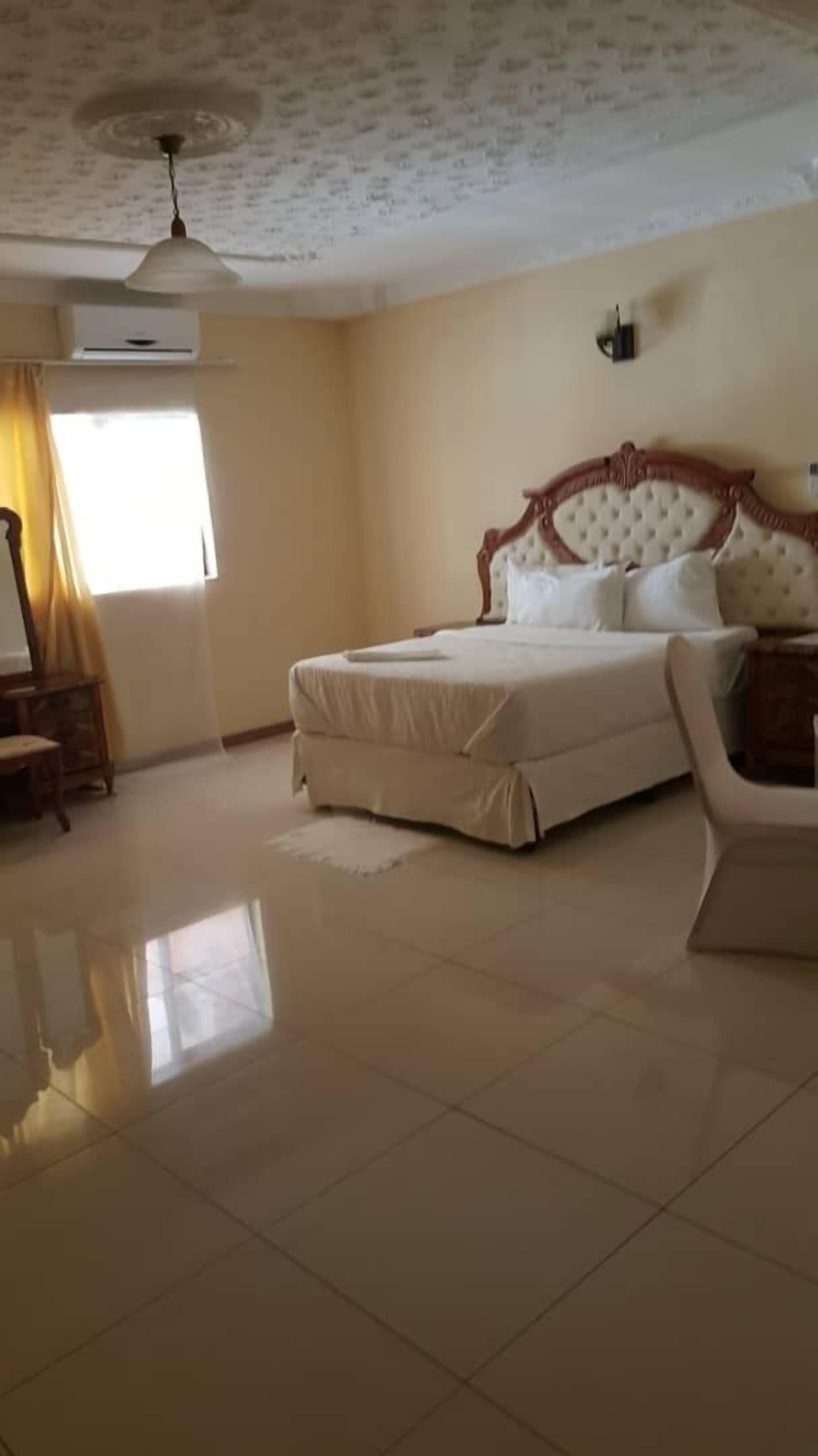 A spacious bedroom with a large bed, a ceiling fan, and a window with curtains.