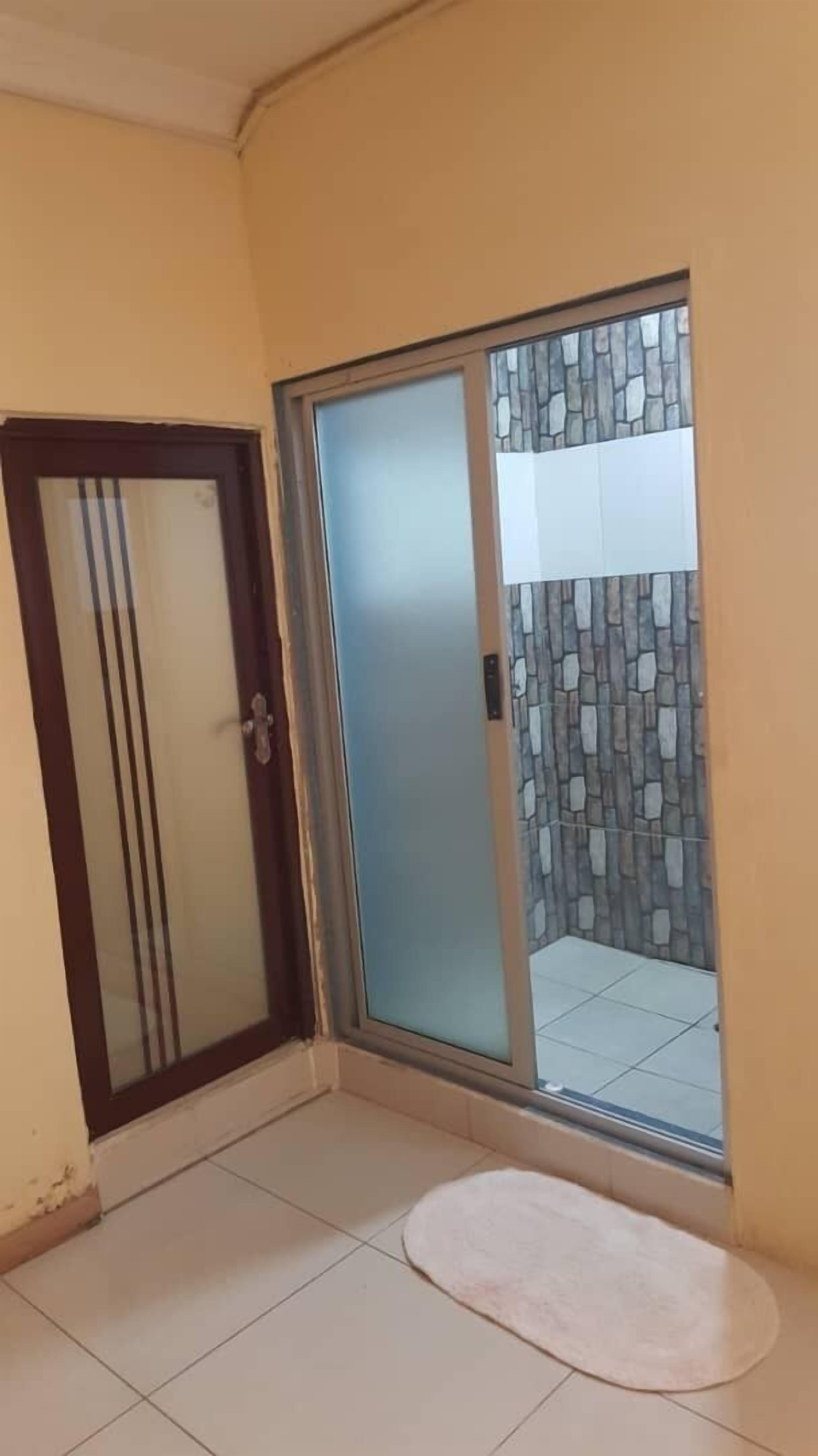 Quarto com porta de vidro deslizante que dá para área externa com piso de azulejos e parede de pedra.