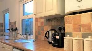 A kitchen with white cabinets, a coffee maker, a kettle, and a dish rack. - Seaside House With Parking (Worthing)