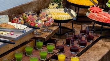 Un buffet proposant une variété de fruits, de fromages et de jus de fruits.