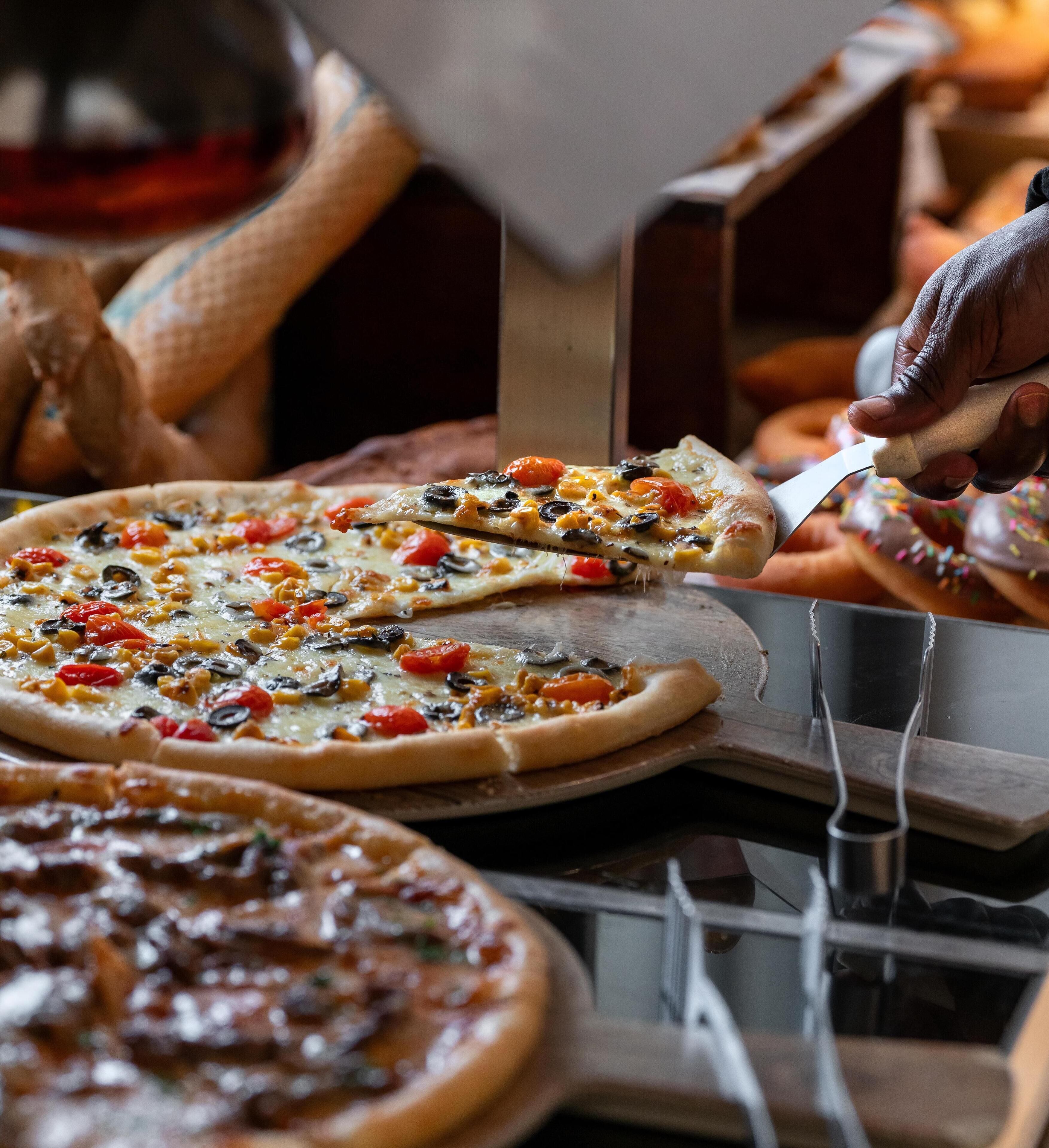 A pizza being served with a variety of toppings.