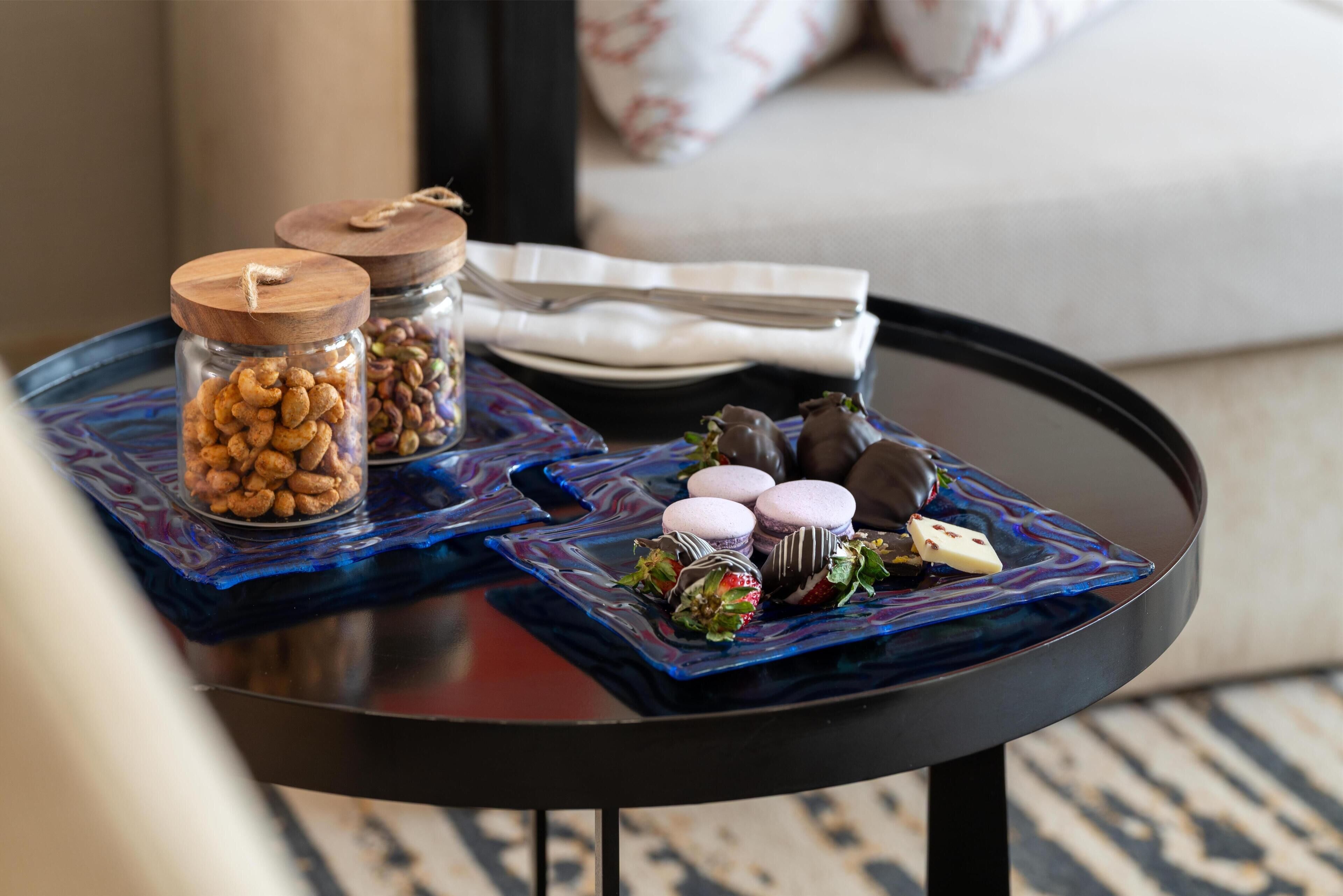 Una bandeja con bocadillos y macarons sobre una mesa redonda en una habitación.