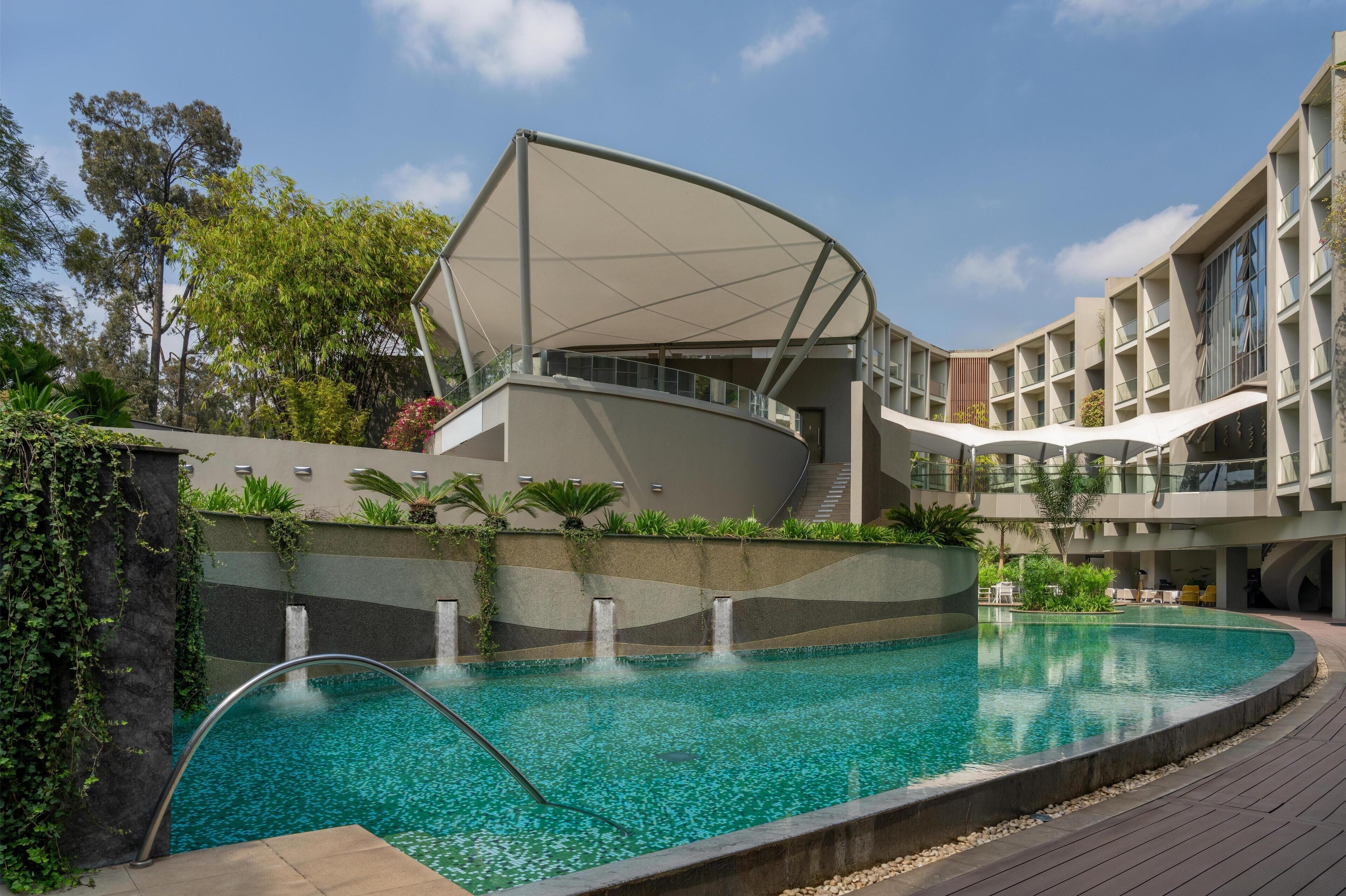 Een buitenzwembad, parasols bij het zwembad en ligstoelen