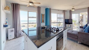 A modern kitchen with a central island, large windows, and a balcony with a view. - The Bay Views (Cape Town)