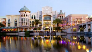 A large, historic building with a central dome and multiple wings, reflecting in a calm body of water. - The Bay Views (Cape Town)