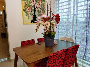 Enjoy meals in this cozy dining area with a wooden table and comfortable seating, surrounded by a beautiful potted plant and a stunning piece of artwork.