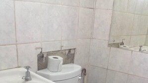 A bathroom with a white sink, toilet, and a mirror above the sink. - Twana Classic Lodge (Choma)