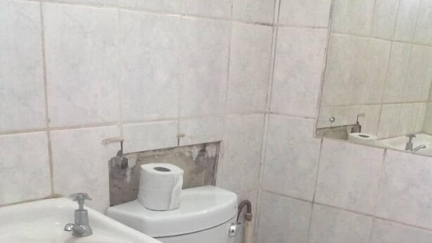 A bathroom with a white sink, toilet, and a mirror above the sink. - Twana Classic Lodge (Choma)