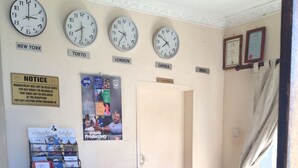 A reception desk with clocks showing New York, Tokyo, London, Zambia, and India. There is a notice about valuables, a magazine rack, and a door labeled "RECEPTION". - Twana Classic Lodge (Choma)