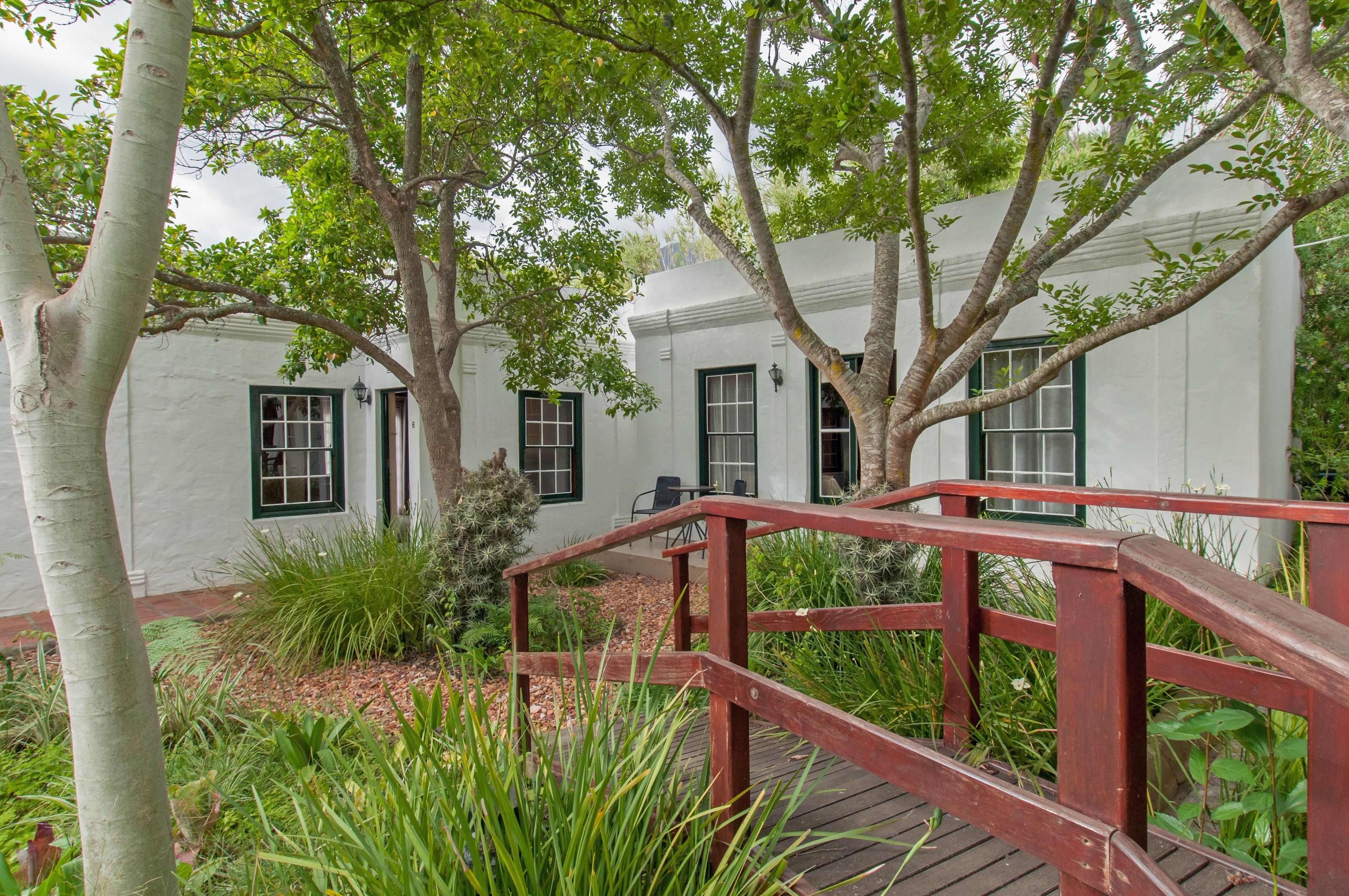A white building with green windows and a wooden deck.