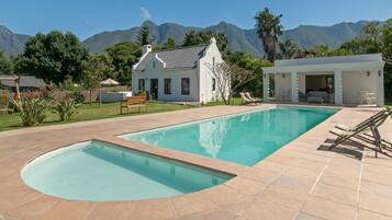Una piscina con una casa y montañas al fondo.