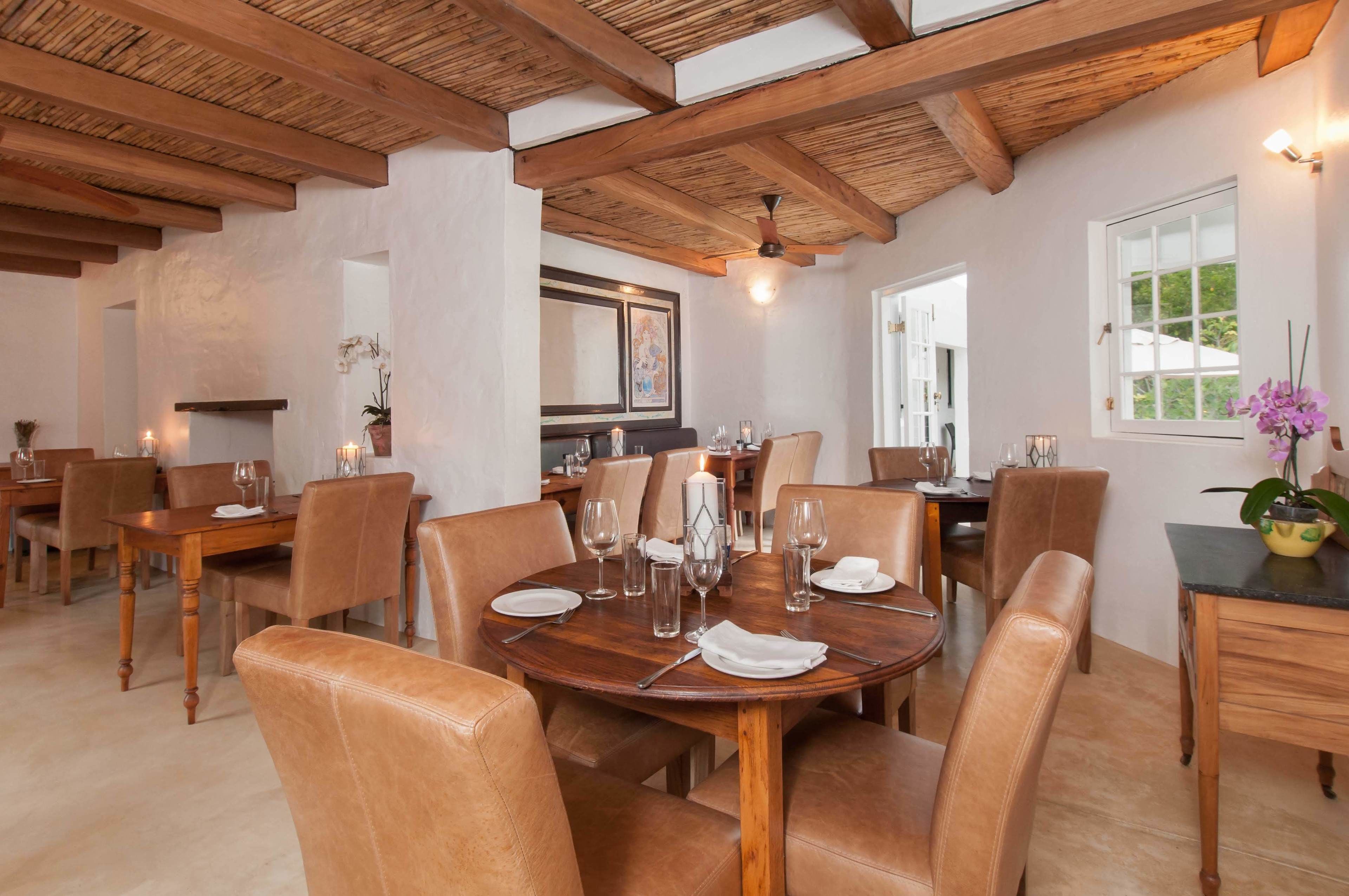 Un espace repas avec des tables et des chaises en bois, un ventilateur de plafond et une fenêtre donnant sur un beau paysage.