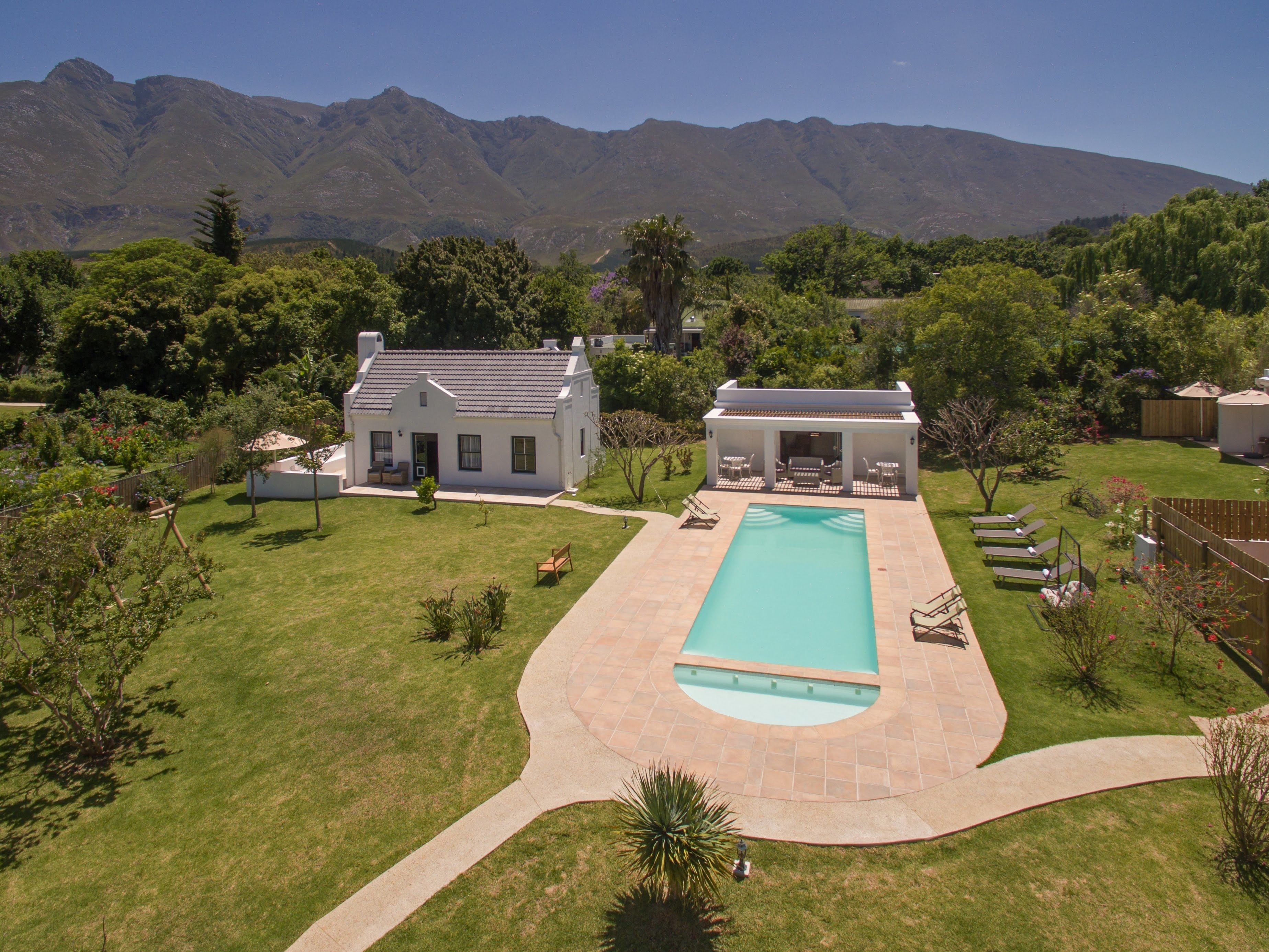 A house with a swimming pool, a patio, and a view of mountains.