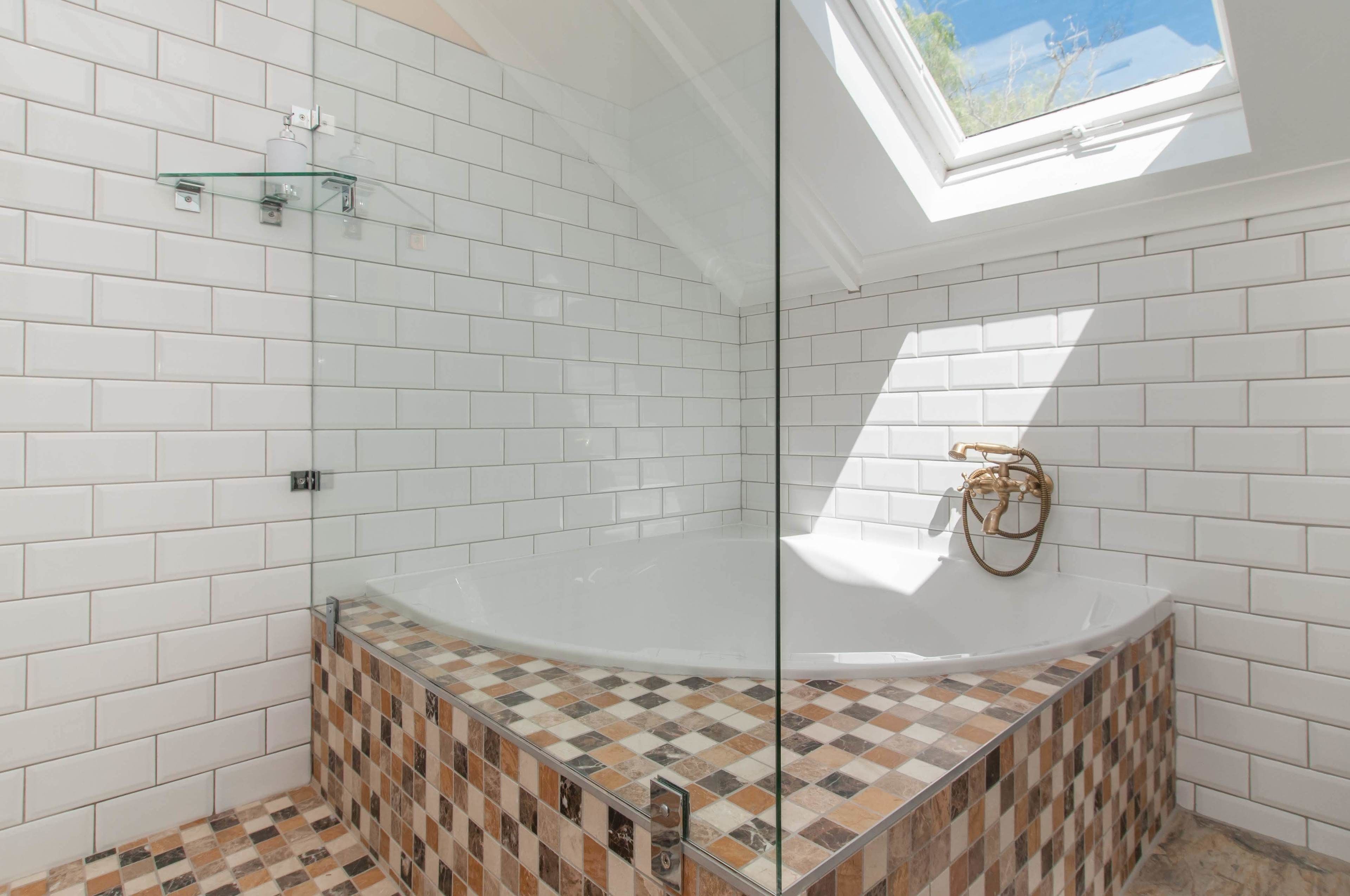 A bathroom with white tiled walls, a glass shower enclosure, and a checkered tile floor.