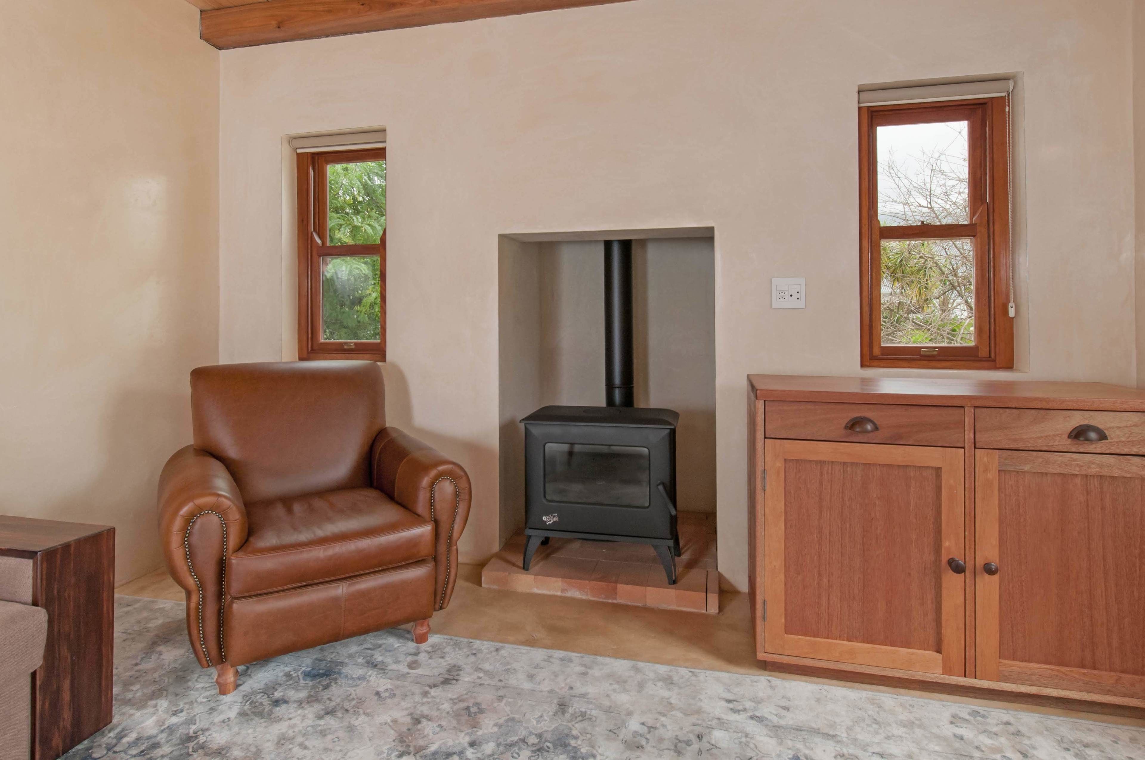 A room with a leather armchair, a wood-burning stove, and a wooden cabinet.