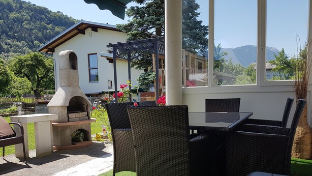 Une terrasse extérieure aménagée avec des meubles en osier, un four en pierre et une vue sur une montagne.