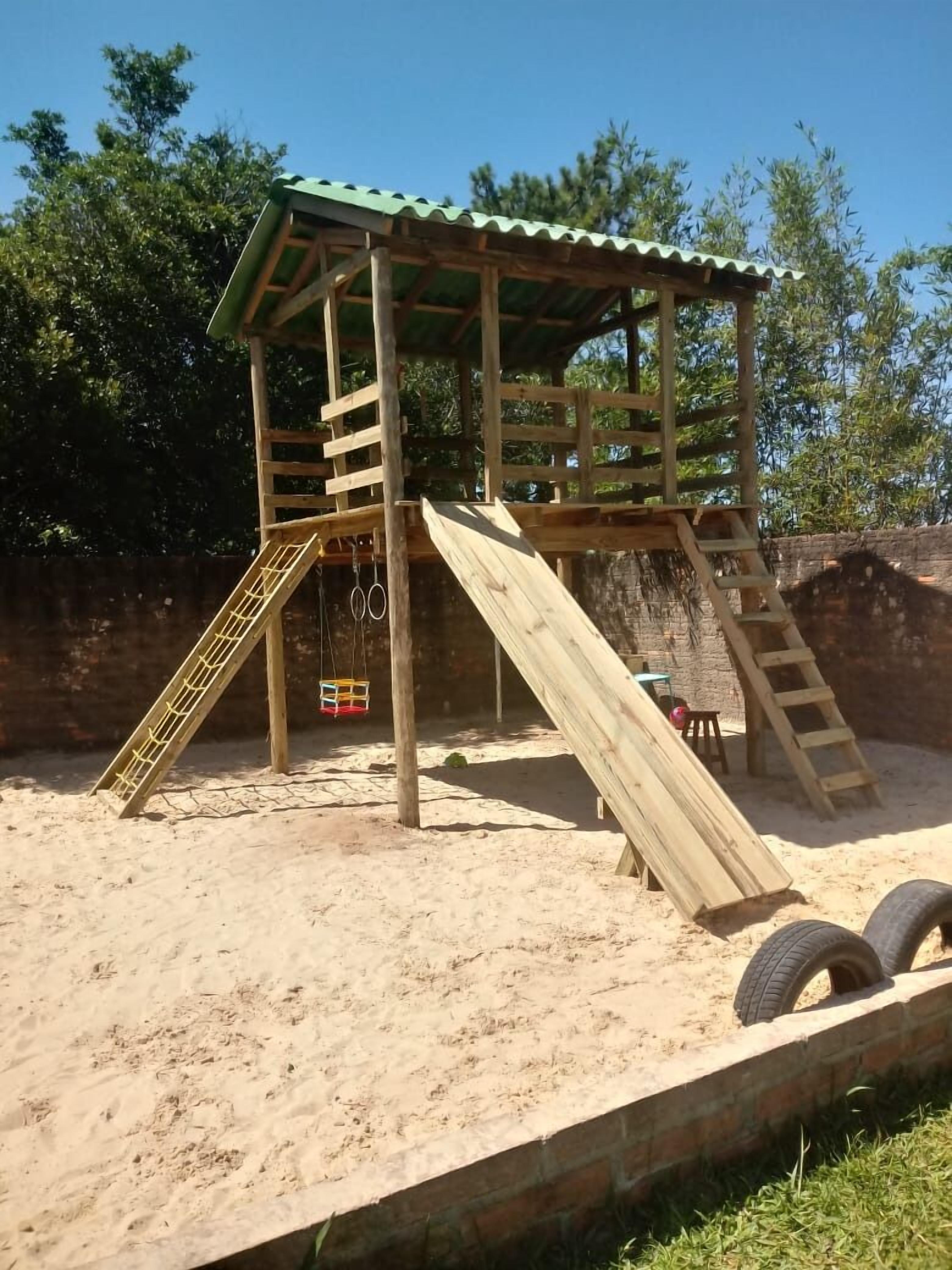 A wooden play structure with a roof, slides, and a ladder.