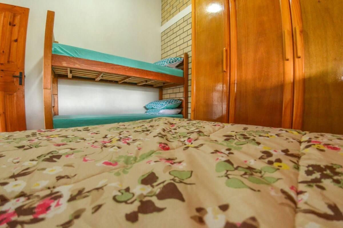 A bedroom with a bunk bed, a wooden wardrobe, and a floral bedspread.