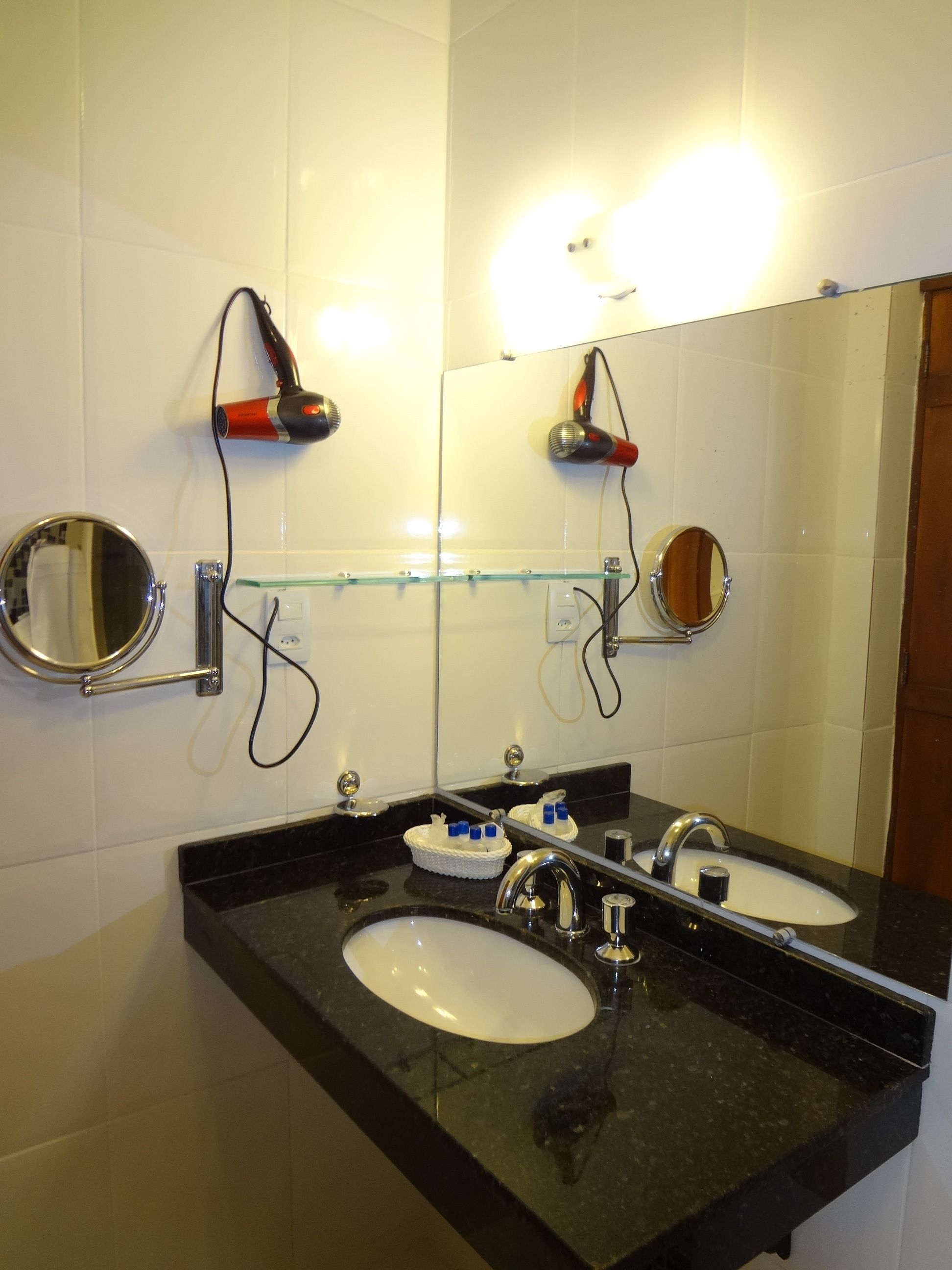 Un baño con dos lavamanos, un espejo grande y un secador de pelo montado en la pared.