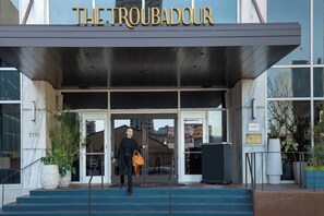 The entrance to The Troubadour with a modern design, featuring a glass facade and a set of stairs leading up to the door. - Troubadour Hotel (New Orleans)