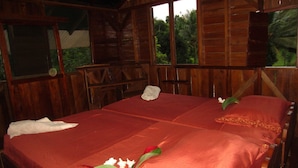 A wooden cabin with a large bed, two pillows, and a red bedspread. - EcoFarm Casa Pequeña (Drake Bay)