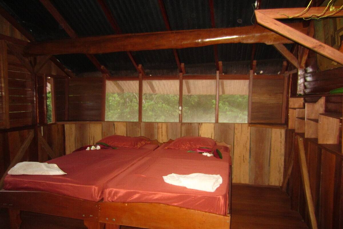 A wooden cabin bedroom with a bed, pillows, and a window.