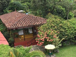 Una casa con techo de tejas, rodeada de abundante vegetación y plantas en flor.