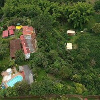 Vista aérea de una zona residencial con varias casas, una piscina y abundante vegetación circundante.