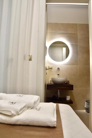 Une salle de bain moderne avec un miroir rond, un lavabo blanc et un meuble-lavabo en bois.