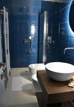 A bathroom with blue tiles, a white toilet, a large white sink, and a shower area. - Les 3 Chambres (Lecce)