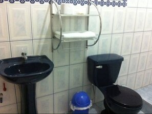 A bathroom with a black sink, a toilet, and a blue bucket. - Lodge Viñas del  Sol (Grocio Prado)