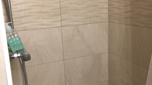 A shower area with beige tiles and a handheld showerhead. - Monteurzimmer Leimen (Leimen)