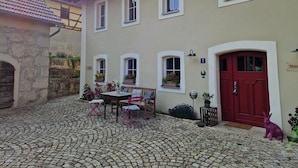 A building with a cobblestone courtyard, a red door, and a number '2' sign.