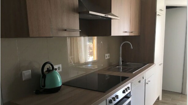 Una cucina moderna con piano cottura a gas, bollitore e pensili in legno.