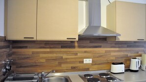 Una cucina con zoccolo in legno, elettrodomestici in acciaio inossidabile e un tostapane.