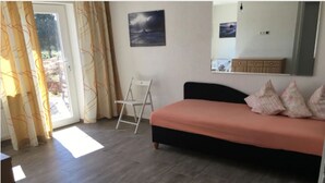 Una camera da letto con un letto, una scala, una finestra con tende e un quadro appeso al muro.