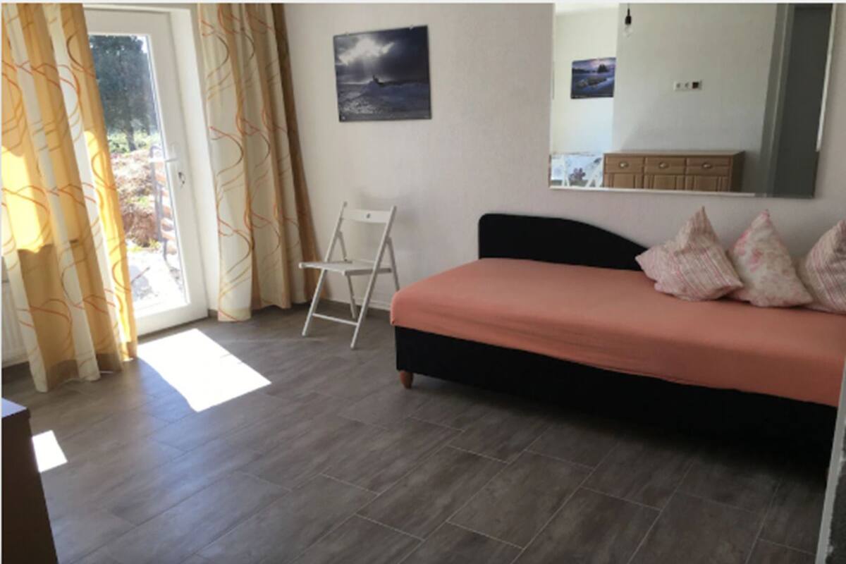 Ein Schlafzimmer mit Bett, einer Himmelsleiter, einem Fenster mit Vorhängen und einem Bild an der Wand.