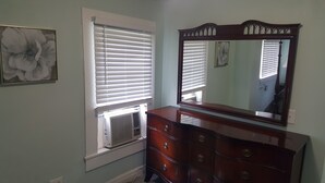 A bedroom with a dresser, a large mirror, and a window with blinds. - Two bedrooms Home Duplex in Historic Downtown lakeland (Lakeland)