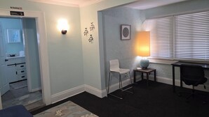 A room with a desk, a chair, a lamp, a wall-mounted light, and a door with a 'No Smoking' sign. - Two bedrooms Home Duplex in Historic Downtown lakeland (Lakeland)