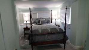 A four-poster bed with a patterned bedspread, two bedside tables with lamps, and a window with blinds. - Two bedrooms Home Duplex in Historic Downtown lakeland (Lakeland)