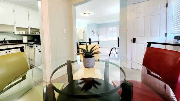 A dining area with a glass table, a potted plant, and a red chair. - Two bedrooms Home Duplex in Historic Downtown lakeland (Lakeland)