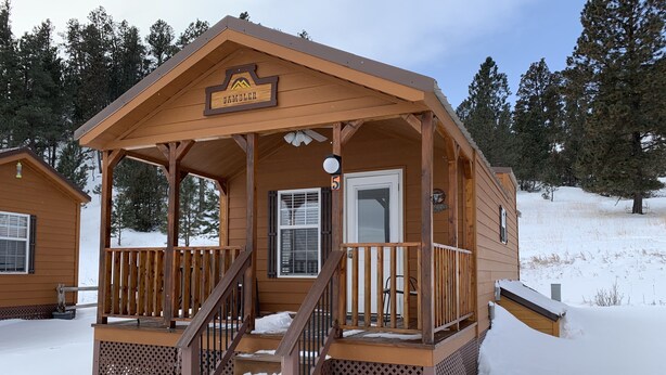 Eine Holzhütte mit Veranda, Treppe und einem Schild mit der Aufschrift 'VAMBLER'.
