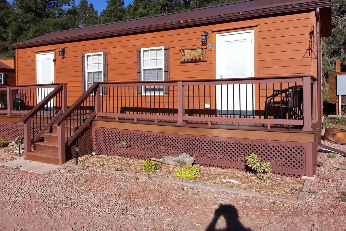 A wooden cabin with a porch, a staircase, and a garage door.