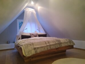 A bedroom with a wooden bed, a canopy bed, and a window with a view. - Pool, sauna, cups, billiards, and lots of nature (Vordernberg)