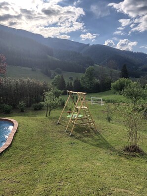 A grassy outdoor area with a wooden swing set, a small pool, and a soccer goal. - Pool, sauna, cups, billiards, and lots of nature (Vordernberg)