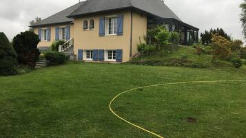 Una casa de dos pisos con techo inclinado, un porche delantero y un césped bien cuidado.