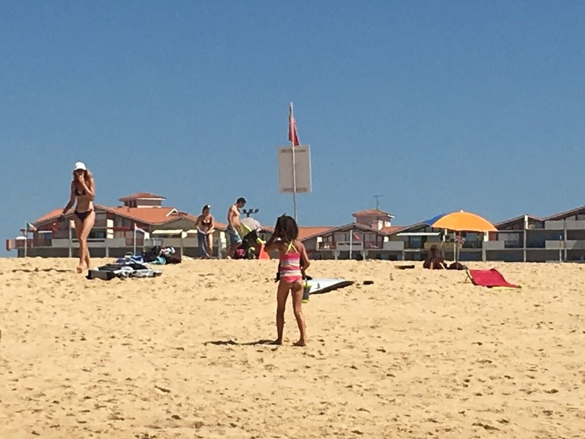 Une plage de sable avec des parasols et un poste de surveillance pour les sauveteurs.